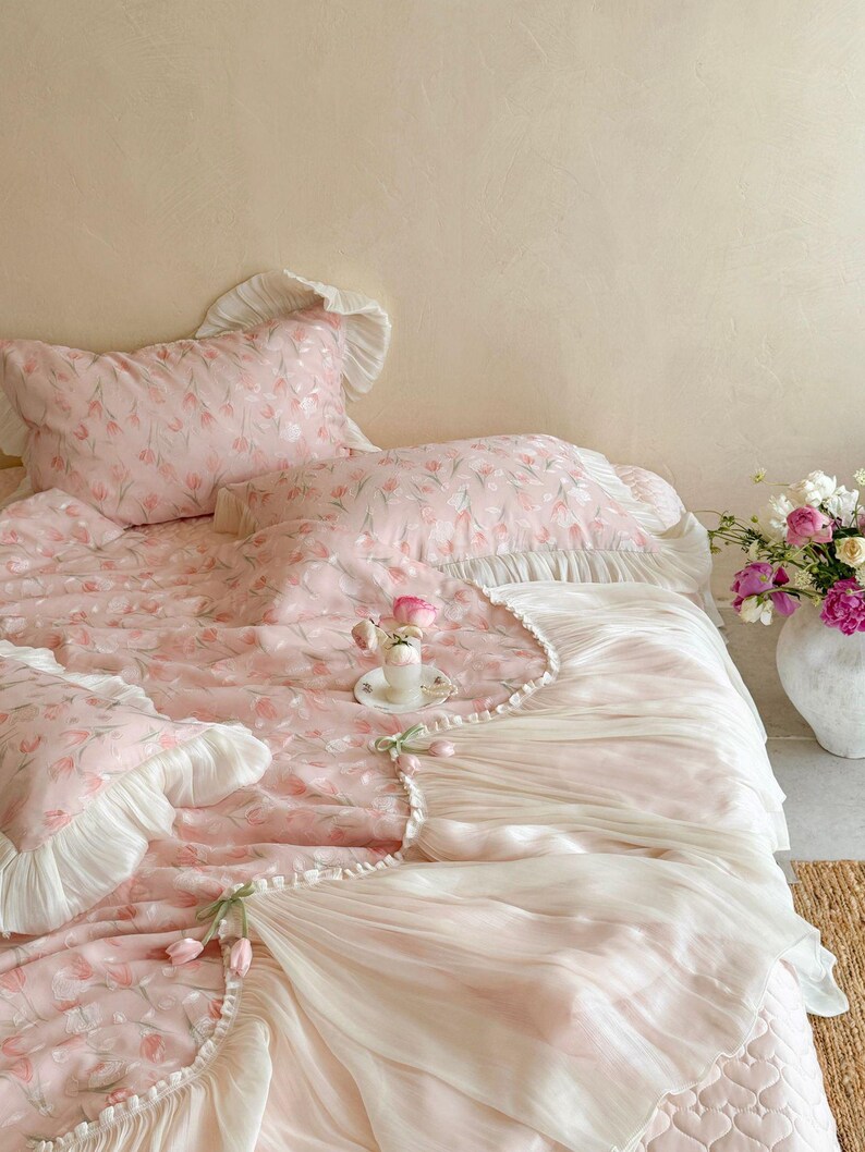 Puede incluir: Un juego de cama que incluye una colcha y fundas de almohada de color rosa claro con un patr&oacute;n de tulipanes. Los bordes est&aacute;n adornados con volantes de tela blanca. Peque&ntilde;os tulipanes decorativos de tela est&aacute;n sujetos al borde.