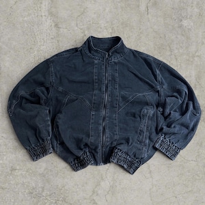 May include: A charcoal black denim bomber jacket featuring a full-length front zip, a stand-up collar, and long sleeves with elasticated cuffs. The jacket includes a gathered elasticated hem and prominent seam detailing across the chest and shoulders.