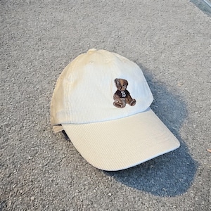 Vintage style baseball cap in cream corduroy with brown teddy bear logo.