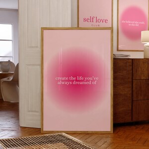 May include: Three framed pink art prints with inspirational quotes. The largest print reads "create the life you've always dreamed of." The other two prints say "self love club" and "she believed she could, so she did."