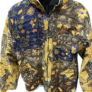 Puede incluir: Chaqueta acolchada con cremallera completa, con un diseño de patchwork. La chaqueta combina telas azul marino y doradas con estampados florales y de cachemira. El cuello y el forro interior tienen un ribete azul claro.