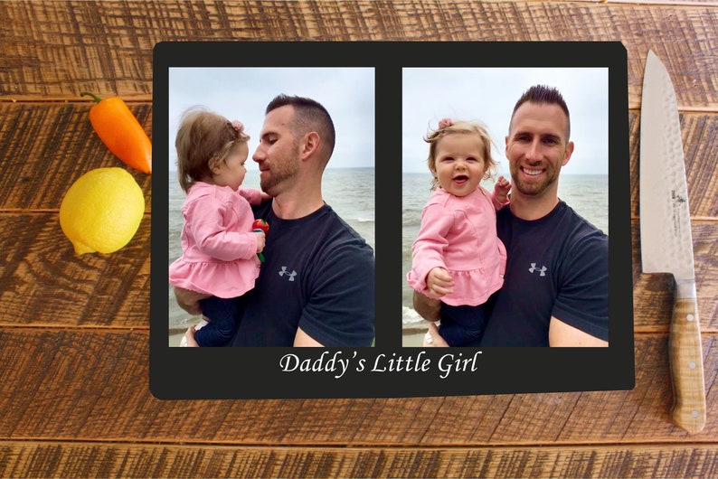 May include: A black framed photo collage with two images of a father holding a young girl. The images are set against a beach background. The text "Daddy's Little Girl" is printed below the images.