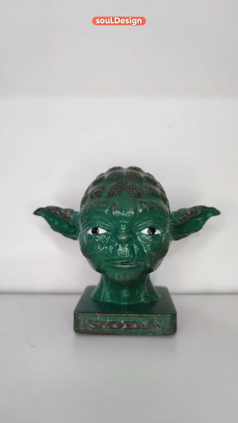 May include: Green Yoda figurine with a distressed paint finish. The figurine is on a square base with the word "Yoda" inscribed on the front.