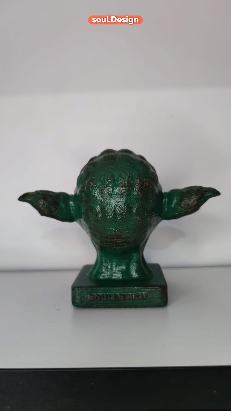 May include: Green Yoda figurine with a distressed paint finish. The figurine is on a base with the words "soulDesign" printed on it.