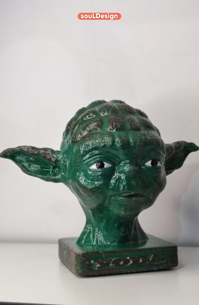 May include: Green Yoda head bust figurine with a textured surface. The bust is on a square base with the word "Yoda" inscribed on it.