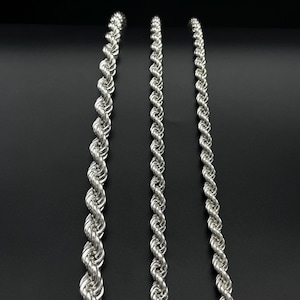 May include: Three silver rope chains of varying thicknesses, displayed against a black background.