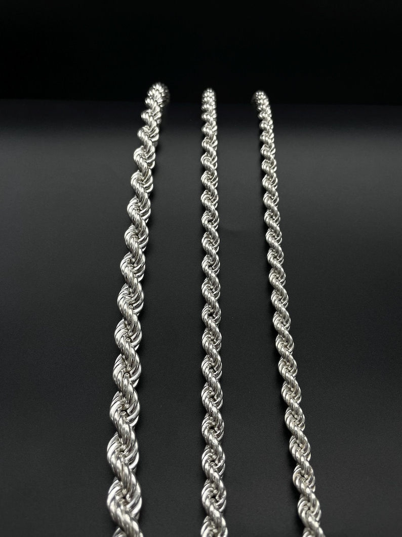 May include: Three silver rope chains of varying thicknesses, displayed against a black background.
