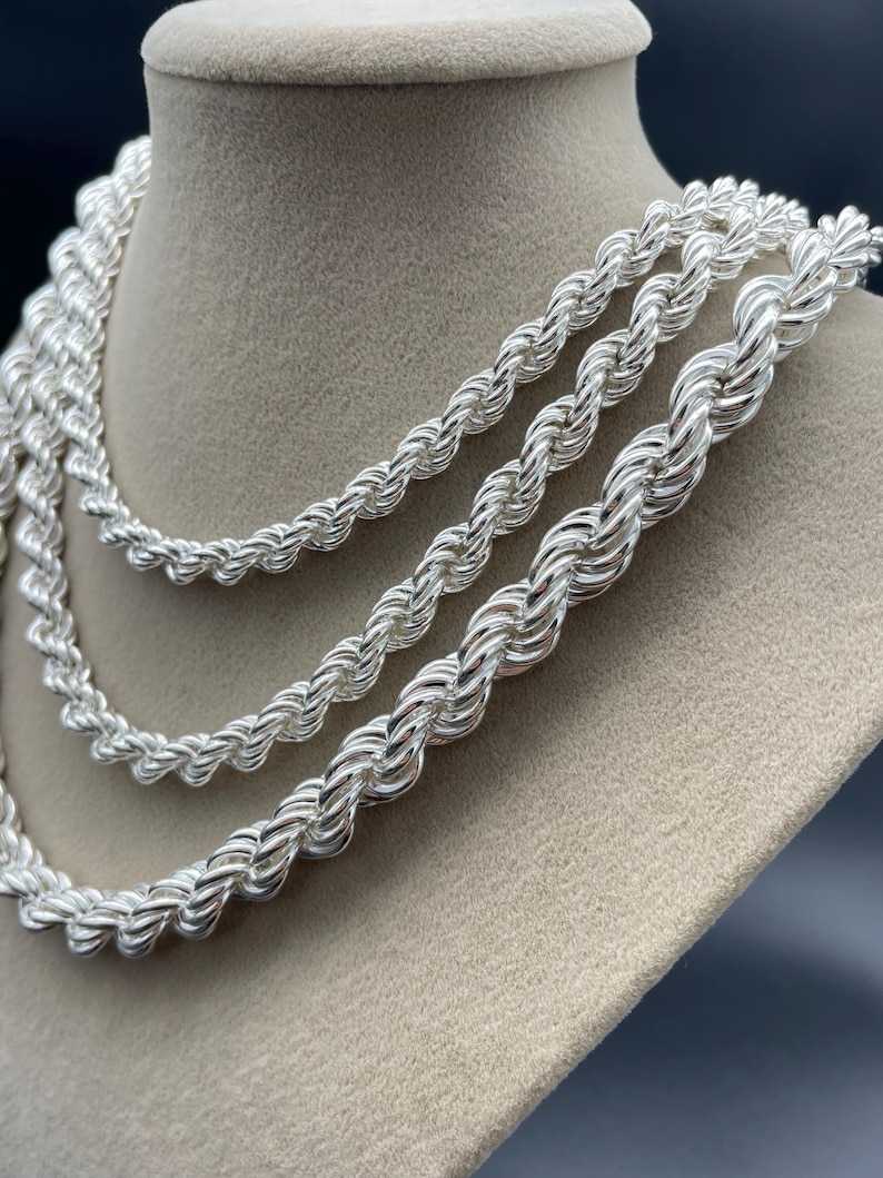 May include: Three silver rope chains of different thicknesses displayed on a tan velvet mannequin bust.