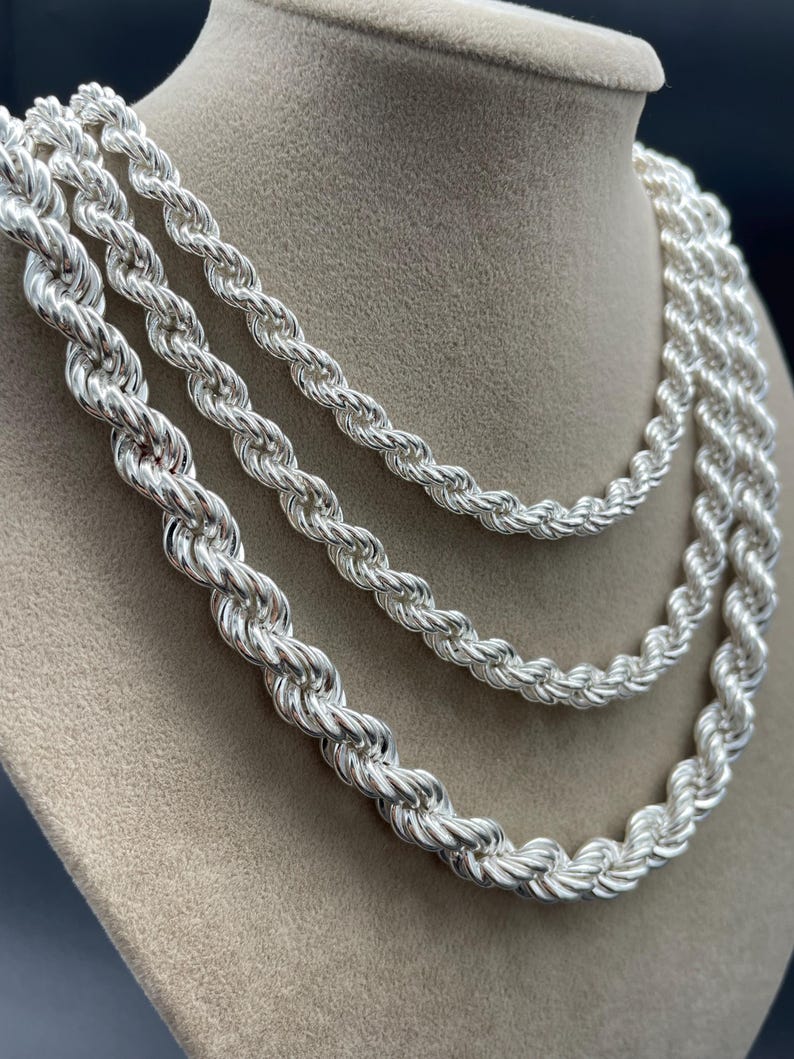 May include: Three silver rope chains of varying thicknesses, displayed on a mannequin's neck.