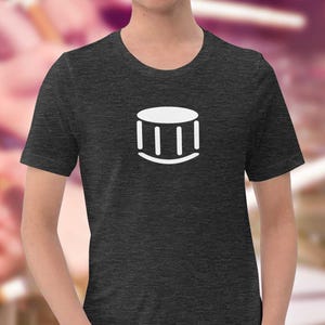 Può includere: Una t-shirt grigio scuro melange con una grafica bianca di una batteria sul davanti.
