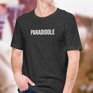 Può includere: Una t-shirt grigio scuro melange con la parola "PARADIDDLE" stampata in bianco sul davanti.
