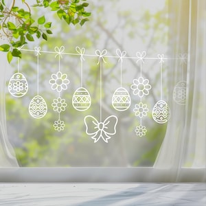 以下が含まれることがあります： 窓に貼る白いステッカーで、イースターエッグ、リボン、花が連なっています。イースターの休日に窓を飾るのに最適なデザインです。