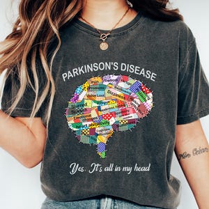 May include: A dark gray t-shirt with a colorful brain graphic and the text "PARKINSON'S DISEASE" and "Yes. It's all in my head".