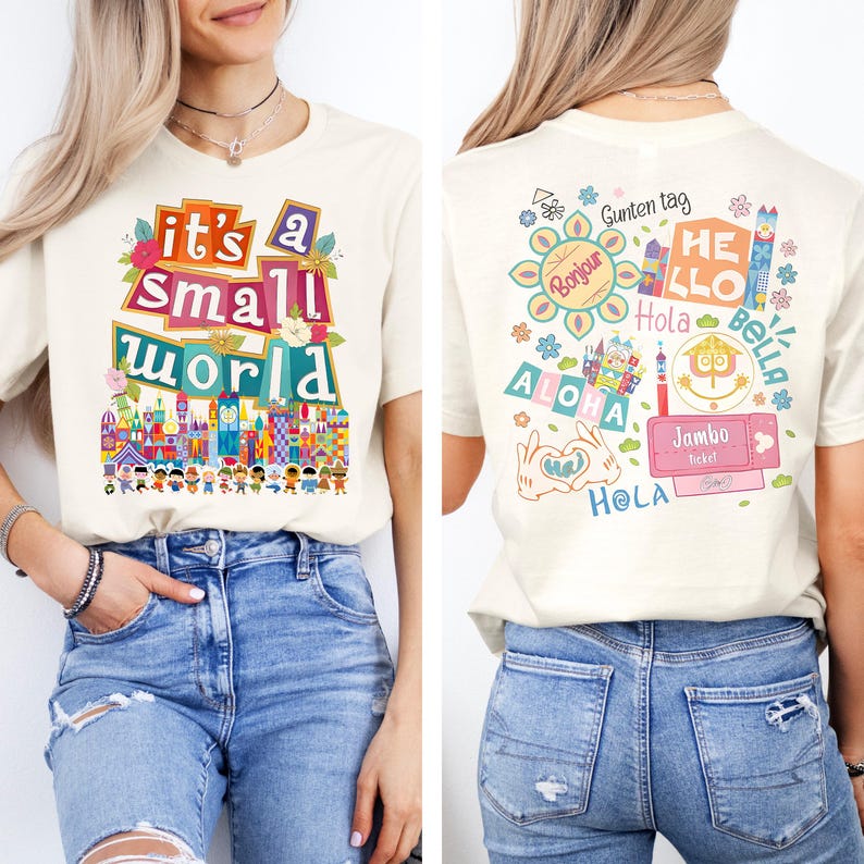 K&ouml;nnte beinhalten: Cremefarbenes T-Shirt mit dem Text "it's a small world" in bunten Buchstaben, mit einem skurrilen Design einer Miniaturstadtlandschaft. Auf der R&uuml;ckseite des Shirts befinden sich verschiedene Gr&uuml;&szlig;e in verschiedenen Sprachen, darunter "Bonjour" und "Hola".