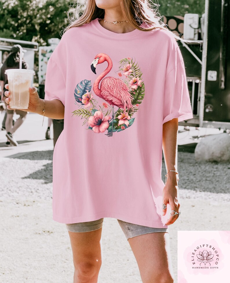 Pu&ograve; includere: T-shirt rosa chiaro con un motivo di fenicottero. Il fenicottero &egrave; rosa con un becco nero, circondato da fiori e foglie tropicali. La maglietta &egrave; rosa chiaro e ha maniche corte.