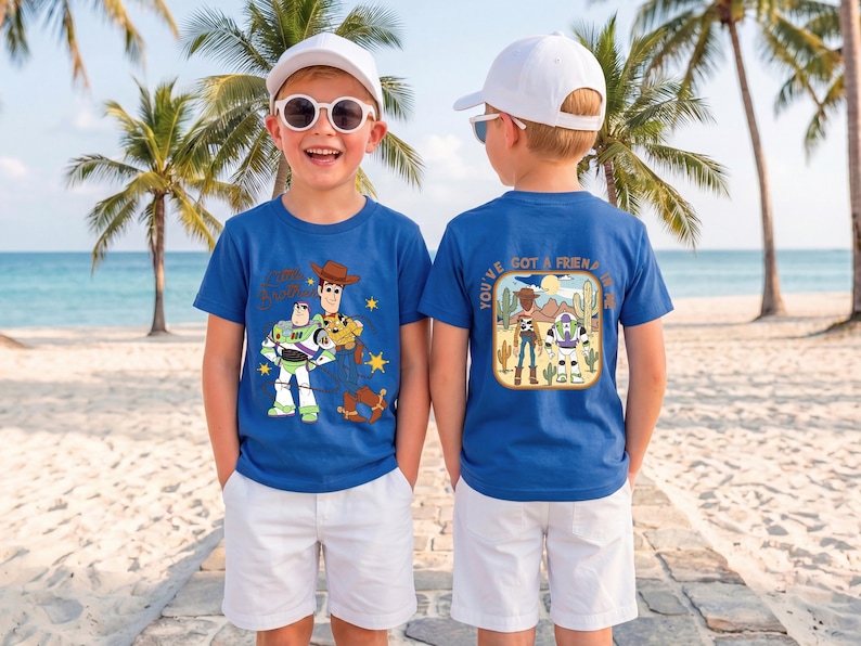 May include: A royal blue short-sleeved t-shirt featuring a graphic of Buzz Lightyear and Woody on the front and a desert scene with the text "You've Got A Friend In Me" on the back, paired with white shorts and a white baseball cap.