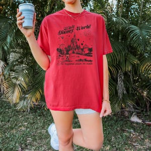 Puede incluir: Camiseta roja con un gr&aacute;fico negro del castillo de Walt Disney World y texto. El texto dice "Walt Disney World" y "The happiest place on earth". La camiseta es de manga corta, de estilo casual.