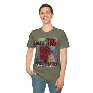 May include: Olive green t-shirt featuring a graphic with the text "RAISE HELL" in red and "PUNCH NAZIS" in white. The graphic depicts a red fist and a figure in a white coat. The shirt is made of a soft material.