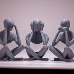 May include: Three gray statues of people sitting with their hands covering their eyes, ears, and mouth. The statues are a representation of the saying "See no evil, hear no evil, speak no evil."