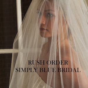 May include: A white bridal veil with a delicate, sheer texture. The veil is draped over a person's head and shoulders. The text "Rush Order Simply Blue Bridal" is visible at the bottom of the image.