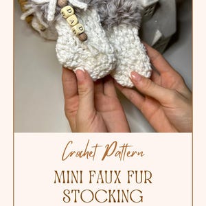 May include: White crocheted mini stocking ornament with faux fur trim. The stocking has a wooden bead with the letters "D-A-D" on it.