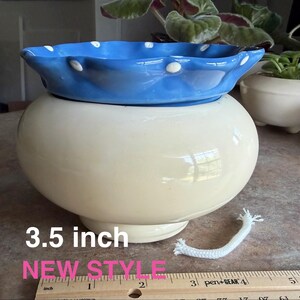 May include: A two-tone ceramic self-watering planter with a cream-colored rounded base and a scalloped blue rim featuring white polka dots. The planter includes a white cotton wick and is labeled 3.5 inch NEW STYLE next to a ruler.