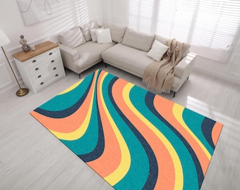 May include: Abstract rug with a wavy pattern in shades of teal, orange, yellow, and black. The rug is laid out on a light wood floor in a living room setting.