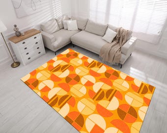 May include: A geometric patterned rug with orange, brown, and cream colored circles and semi-circles. The rug is laid out on a light wood floor in a room with a white couch.