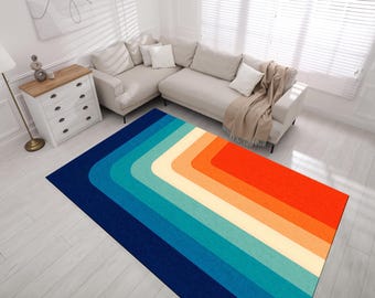 May include: A colorful area rug with a geometric design featuring a series of curved stripes in shades of blue, orange, and cream. The rug is laid out on a light wood floor in a living room setting.
