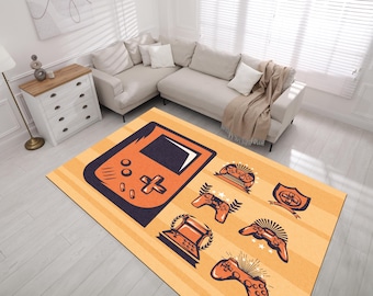 Puede incluir: Una alfombra rectangular con un diseño de videojuego retro. La alfombra presenta un gran gráfico de consola de juegos portátil naranja y azul marino, junto con varias ilustraciones de controladores y trofeos sobre un fondo amarillo a rayas. La alfombra está colocada en una sala de estar.