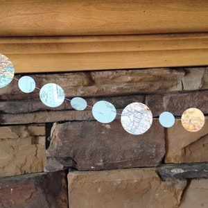 Könnte beinhalten: Eine blaue und weiße Girlande mit Kartenmotiven und Kreisen in verschiedenen Größen. Die Girlande hängt an einer Steinwand.