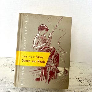 May include: Vintage book titled "The New More Streets and Roads" with a yellow band. The cover features an illustration of a boy fishing. The book is part of the "Basic Readers" series, with a light gray background.