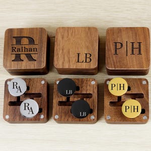 May include: Six wooden boxes and matching cufflinks sets. The boxes are engraved with initials and names. The cufflinks are silver, black, and gold, each with initials. A personalized gift idea.