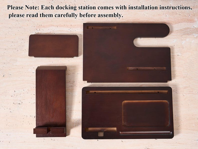 May include: A disassembled wooden docking station with multiple pieces. The pieces are various shapes and sizes, including a rectangular phone holder, a tray, and a larger piece with a curved edge. The wood has a dark brown finish. The text "Please Note: Each docking station comes with installation instructions, please read them carefully before assembly." is visible.