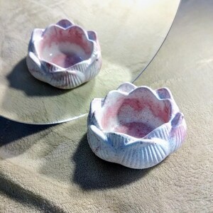 Könnte beinhalten: Eine weiße Keramik-Lotusblüten-Schale mit rosa Akzenten. Die Schale ist flach und hat eine abgerundete Form. Sie ist perfekt für die Aufbewahrung von kleinen Gegenständen wie Schmuck oder Nippes.