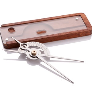 May include: A silver protractor with a wooden case. The protractor has a circular scale with markings in degrees. The case is made of dark wood and has a clear plastic window.