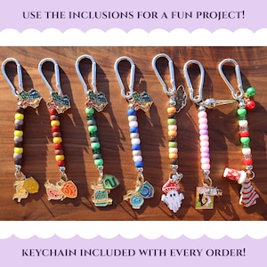 May include: A collection of keychains with colorful beaded strands and decorative charms. Each keychain features a different charm, including a mushroom, a ghost, and a gift box. The text "USE THE INCLUSIONS FOR A FUN PROJECT!" is at the top.