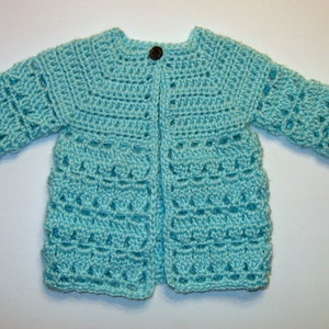 May include: A light blue crocheted cardigan with a button closure. The cardigan has a delicate stitch pattern and is perfect for a baby or toddler.