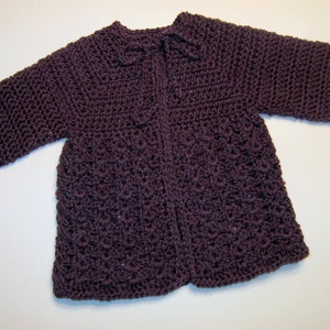 May include: A purple crocheted cardigan with a tie at the neck.