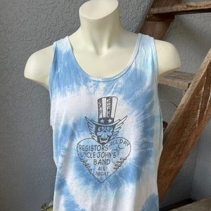 May include: A blue tie-dye tank top with a white heart-shaped graphic featuring a skull wearing a top hat with stars and stripes. The graphic also includes the text "Resistors All Day Uncle John's Band All Night".
