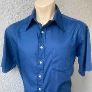 May include: A solid blue short-sleeved button-down shirt with a single pocket on the left side.