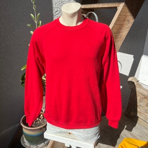 Könnte beinhalten: Ein langärmliger roter Pullover mit Rundhalsausschnitt und Raglanärmeln.