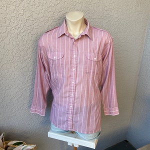 May include: A pink and white striped long-sleeved button-down shirt with two flap pockets on the chest.