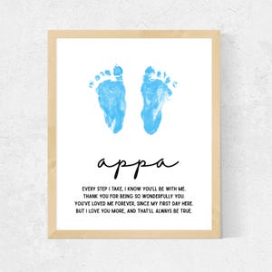 May include: A framed print with two blue baby footprints and the word "appa" in cursive. The text below reads: "Every step I take, I know you'll be with me. Thank you for being so wonderfully you..." A sentimental gift.