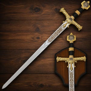 May include: A decorative sword featuring a silver blade with intricate gold-toned filigree engravings. The hilt has a black grip, gold-toned crossguard, and a pommel displaying a Star of David emblem. A second matching sword is mounted on a wooden plaque.