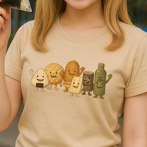 May include: A beige short-sleeved t-shirt featuring a graphic print of six anthropomorphic food and drink items, including an onigiri, a melon pan, a fried snack, a sandwich, a Boss coffee can, and a green tea bottle, all with smiling faces.