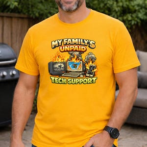 Peut inclure: T-shirt jaune moutarde avec l'inscription "MY FAMILY'S UNPAID TECH SUPPORT". Le graphisme représente une télévision, un ordinateur et un smartphone en feu. Un design humoristique sur le thème du support technique.