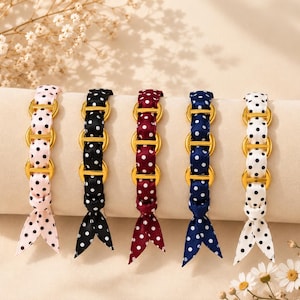 Peut inclure: Cinq bracelets composés de maillons métalliques dorés entrelacés de rubans en tissu à pois. Les rubans sont déclinés en rose clair, noir, bordeaux, bleu marine et blanc, chacun noué à l'extrémité pour former un accessoire uniforme et décoratif.
