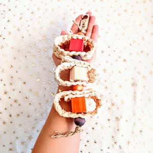 May include: A woven bird toy with three colorful wooden blocks and beads. The toy is attached to a natural twine rope with a wooden tag that says "Birdie".