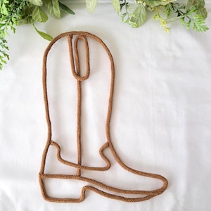 May include: A brown rope boot shaped wall decor. The boot is made of a thick brown rope and is a simple design.